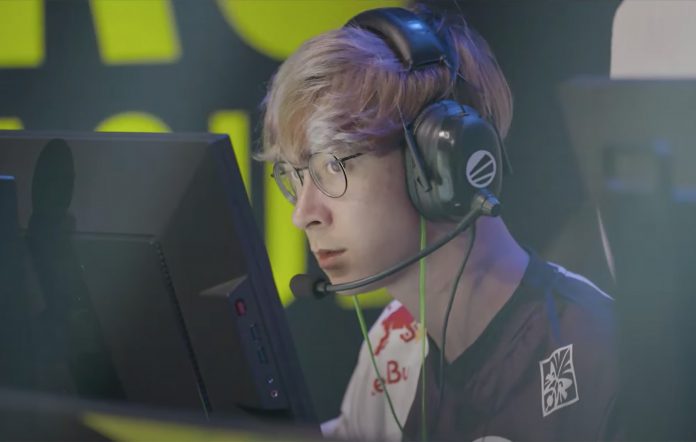 A bespectacled player sitting in front of the monitor, wearing headphones with a mic